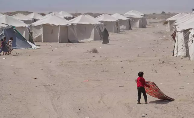 A displaced Yemeni pulls his mattress at Al-Firdaws camp in Ras Imran, on the western outskirts of Aden, Yemen, Tuesday, Sept. 22, 2026. (AP Photo/Abdulnasser Alseddik)