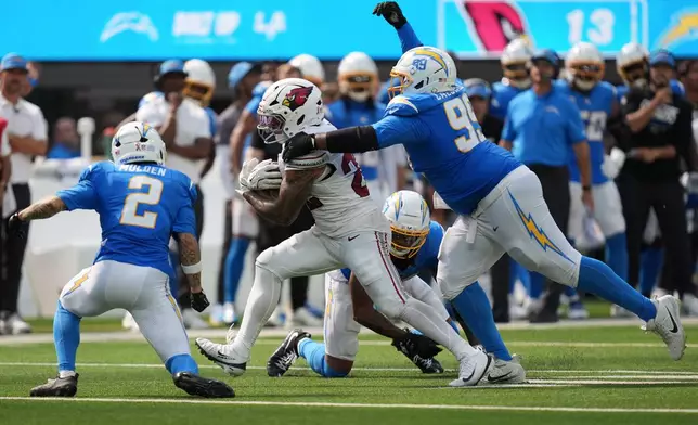 Arizona Cardinals running back Tyler Allgeier, middle, runs against Los Angeles Chargers cornerback Elijah Molden (2), defensive tackle Jamaree Caldwell (99) and linebacker Del'Shawn Phillips during the second half of an NFL football game, Sunday, Sept. 13, 2026, in Inglewood, Calif. (AP Photo/Gregory Bull)