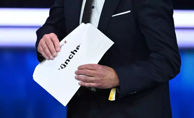 Thomas Weikert, President of the German Olympic Sports Confederation (DOSB), opens the envelope on stage at the extraordinary DOSB General Assembly to select Germany's Olympic bid for 2036, 2040, or 2044, in Baden-Baden, Germany, Saturday Sept. 26, 2026. Munich is Germany's candidate city. (Marijan Murat/dpa via AP)