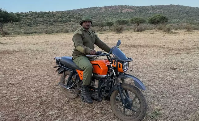 In this photo taken with a smartphone, Mara Siena ranger Joshua Kijape stands beside his electric motorcycle, which he uses while patrolling the Maasai Mara, Kenya, Saturday, Aug. 29, 2026. (AP Photo/Allan Olingo)