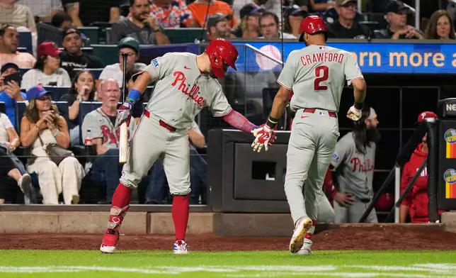 Philadelphia Phillies' Kyle Schwarber, left, greets Justin Crawford (2) after Crawford hit a sac fly during the eighth inning of a baseball game against the New York Mets, Thursday, Sept. 17, 2026, in New York. (AP Photo/Seth Wenig)