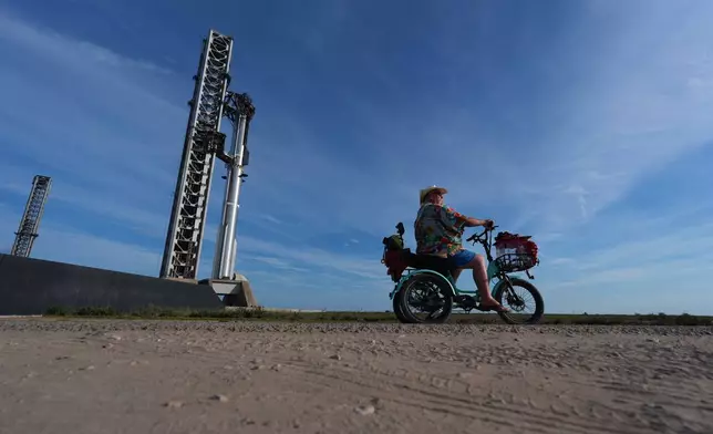David Orr rides his bike past SpaceX's mega rocket Starship as it is prepared for a test flight from Starbase, Texas, Sunday, Sept. 27, 2026. (AP Photo/Eric Gay)