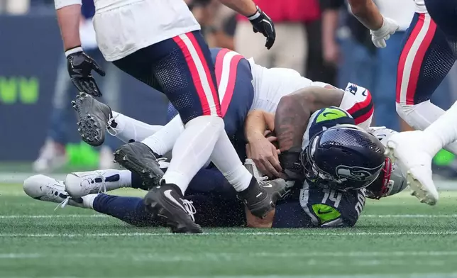 Seattle Seahawks quarterback Sam Darnold, (14) is sacked by New England Patriots linebacker Dre'mont Jones, behind, during the first half an NFL football game, Wednesday, Sept. 9, 2026, in Seattle. (AP Photo/Lindsey Wasson)