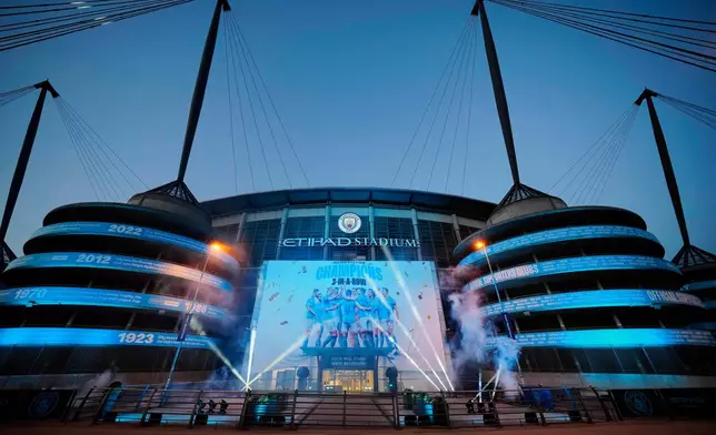 FILE - A banner celebrating their title win is illuminated outside Manchester City's Etihad stadium in Manchester, England, Saturday, May 20, 2023. (AP Photo/Jon Super, File)