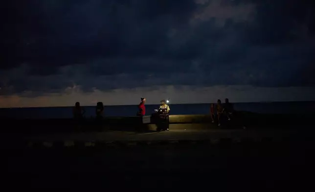 A woman speaks with a vendor on the Malecon seawall during a blackout in Havana, Cuba, Friday, Sept. 18, 2026. (AP Photo/Ramon Espinosa)