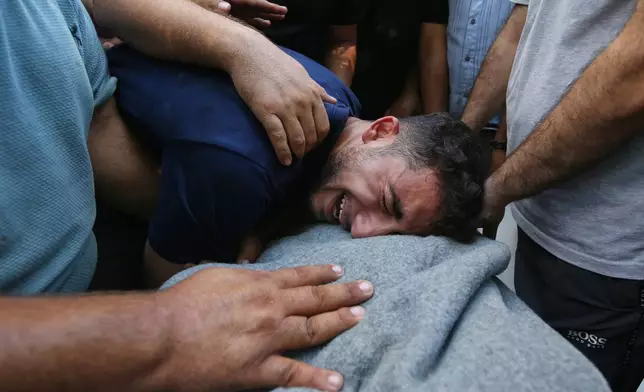 Mourners cry over the body of Palestinian Bassir al Barsh, who was killed in an Israeli airstrike, at a hospital in Gaza city, Saturday, Sept. 19, 2026. (AP Photo/Yousef Al Zanoun)