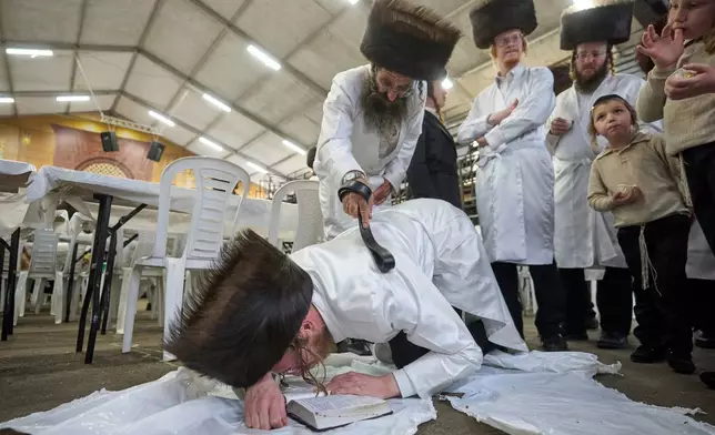 An ultra-Orthodox Jewish man whips a member of his Hasidic dynasty with a leather strap as a symbolic punishment for his sins last year, during the traditional Malkot (whipping in Hebrew) ceremony ahead of Yom Kippur that begins at sunset, Beit Shemesh, Israel, Sunday, Sept. 20, 2026. (AP Photo/Ohad Zwigenberg)