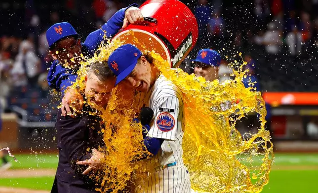 New York Mets' Carson Benge, right, hugs announcer Steve Gelbs, left, as he gets doused with Gatorade after breaking the Mets rookie season record for hits in New York, Saturday, Sept. 19, 2026. (AP Photo/Noah K. Murray)