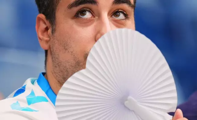 A man uses a fan to cool off during the La Liga soccer match between Real Madrid and Malaga at the Bernabeu stadium in Madrid, Spain, on Aug. 30, 2026. (AP Photo/Manu Fernandez)