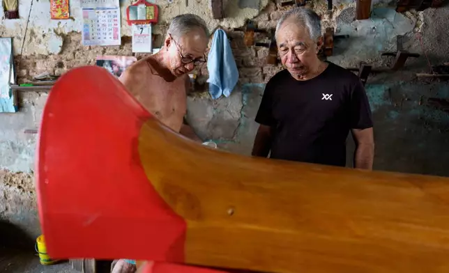 Bothers Goh Khuay Par, left, and Goh Khuay Hou inspect a completed Mei Hua coffin at their family's workshop in Muar, Malaysia, Monday, Sept. 7, 2026. (AP Photo/Vincent Thian)