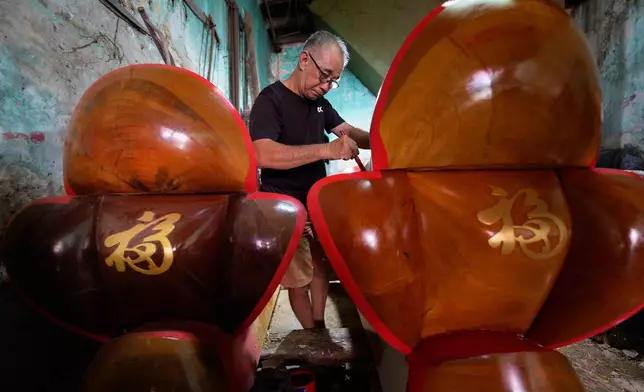 Goh Khuay Hou applies red paint to a Mei Hua coffin at his family workshop in Muar, Malaysia, Tuesday, July 14, 2026. (AP Photo/Vincent Thian)