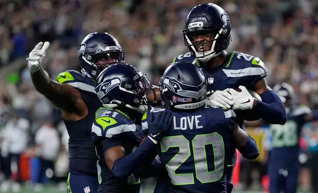 Seattle Seahawks cornerback Josh Jobe, top right, celebrates after intercepting a pass in the end zoe with teammates including safety Julian Love, bottom right, during the second half of an NFL football game against the New England Patriots, Wednesday, Sept. 9, 2026, in Seattle. (AP Photo/Stephen Brashear)