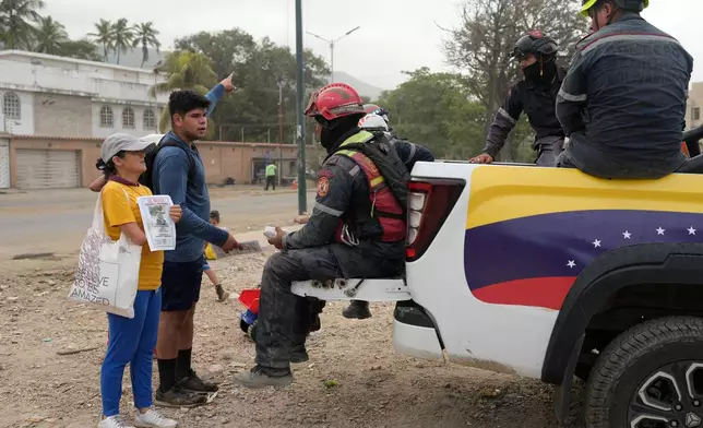 Pedro Gomez asks rescuers for information about his cousin, Andres Molina, who has been missing since the earthquake, in La Guaira, Venezuela, Saturday, Aug. 22, 2026. (AP Photo/Ariana Cubillos)