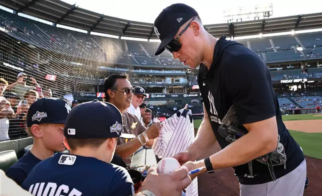 New York Yankees' Aaron Judge, right, gives autographs to fans before a baseball game against the Los Angeles Angels, Monday}, Aug. 31, 2026, in Anaheim, Calif. (AP Photo/Wally Skalij)