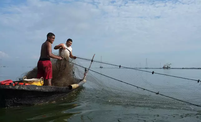 Jackson Silva, left, and Jose Lopez pull in their fishing net near oil installations on Lake Maracaibo in Cabimas, Venezuela, Wednesday, Sept. 2, 2026. (AP Photo/Ariana Cubillos