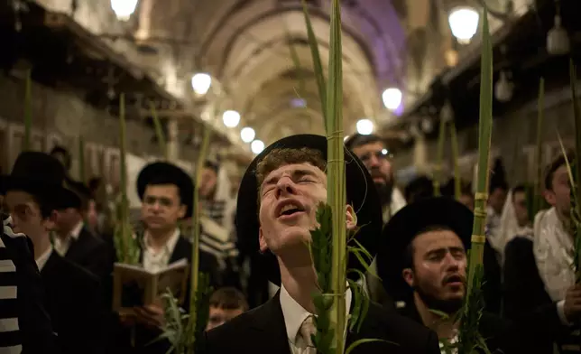 Orthodox Jewish men pray in front of the gate at Souq Al-Qattanin, or Cotton Merchants' Market, one of the entrances to the Al-Aqsa Mosque compound in the Old City of Jerusalem, Monday, Sept. 28, 2026, during morning prayers for the Jewish holiday of Sukkot. (AP Photo/Leo Correa)