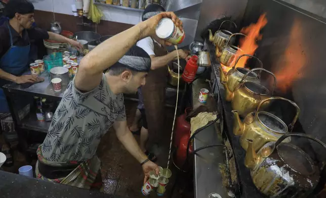 A tea seller pours milk from a can as he prepares tea at a market in Houthi-controlled Sanaa, Yemen, Monday, Sept. 28, 2026. (AP Photo/Osamah Abdulrahman)