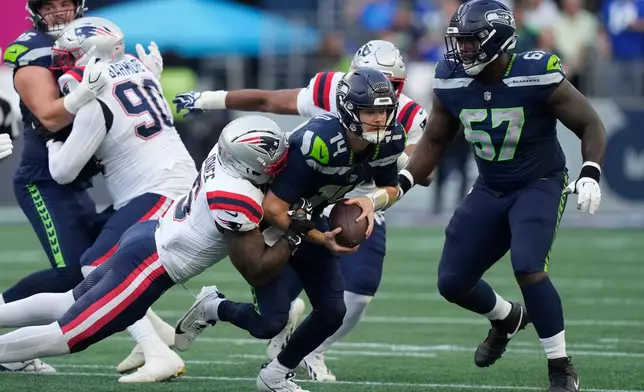 Seattle Seahawks quarterback Sam Darnold, center, is sacked by New England Patriots linebacker Dre'mont Jones, left, as Seattle Seahawks linebacker Connor O'Toole is at right, during the first half of an NFL football game, Wednesday, Sept. 9, 2026, in Seattle. (AP Photo/Stephen Brashear)