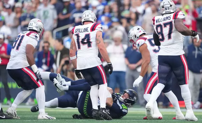 Seattle Seahawks quarterback Sam Darnold, down center, is sacked by New England Patriots linebacker Dre'mont Jones, behind, as New England Patriots linebacker Elijah Ponder (91), linebacker Robert Spillane (14), linebacker Christian Elliss (53), and defensive tackle Milton Williams (97) look on during the first half an NFL football game , Wednesday, Sept. 9, 2026, in Seattle. (AP Photo/Lindsey Wasson)