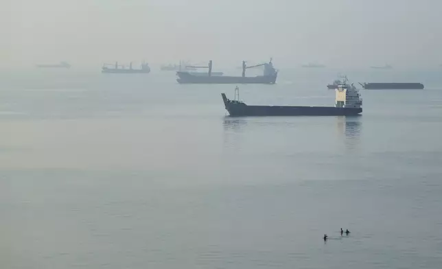 People wade in the water as cargo ships are anchored in the Strait of Hormuz off Bandar Abbas, Iran, early Monday, Sept. 28, 2026. (Amirhosein Khorgooi/ISNA via AP)