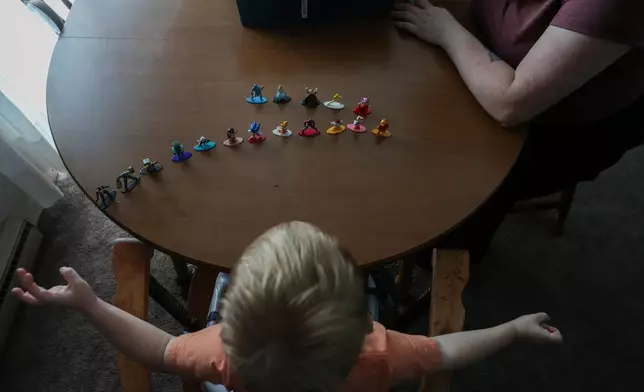 Meygan Maloney and her son, Callum Wilson, 3, play with figurines Friday, Aug. 28, 2026, at their home in Hartford City, Ind. (AP Photo/Cara Penquite)