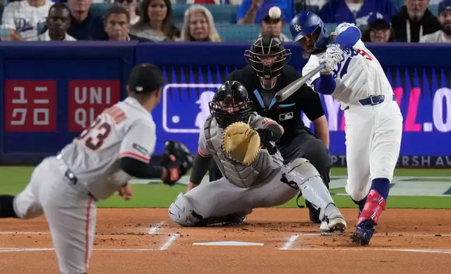 Los Angeles Dodgers' Mookie Betts, right, hits a solo home run as San Francisco Giants pitcher Cesar Perdomo, left, and catcher Drew Cavanaugh watch during the first inning of a baseball game Friday, Sept. 18, 2026, in Los Angeles. (AP Photo/Mark J. Terrill)