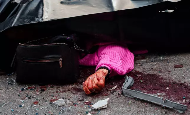 The lifeless body of woman lies on a street in front of an office building damaged in a Russian drone strike on Kyiv, Ukraine, Friday, Sept. 25, 2026. (AP Photo/Evgeniy Maloletka)