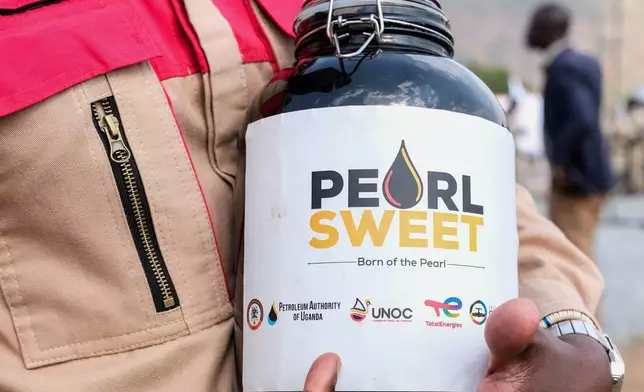 A worker holds a container with a crude oil sample at the Kingfisher oil field, operated by China National Offshore Oil Corporation (CNOOC), near Hoima, Uganda, Wednesday, Sept. 2, 2026. (AP Photo/Hajarah Nalwadda)