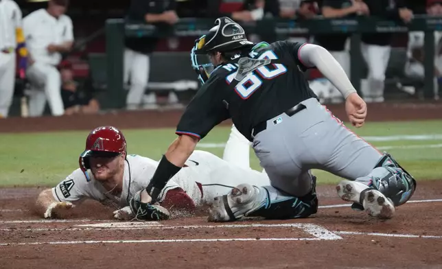 Arizona Diamondbacks' Pavin Smith, left, steals home under a tag by Miami Marlins catcher Joe Mack, right, in the third inning of a baseball game, Monday, Sept 14, 2026, in Phoenix. (AP Photo/Rick Scuteri)