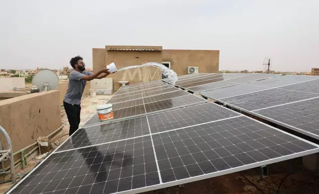 A technician cleans solar panels installed on the roof of a home in Omdurman, on the outskirts of Khartoum, Sudan, July 23, 2026. (AP Photo/Mohnd Blal)