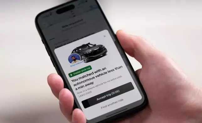 A client orders an autonomous car on his mobile phone in London, Tuesday, Sept. 1, 2026 as Uber officially launches the first hailable autonomous cabs in London.(AP Photo/Frank Augstein)