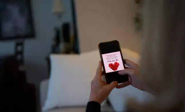 Debra Fox, who had $58,000 stolen from her in a romance scam, looks at a message on her phone that her scammer sent as she sits at home, Wednesday, May 13, 2026, in Arvada, Colo. (AP Photo/David Goldman)