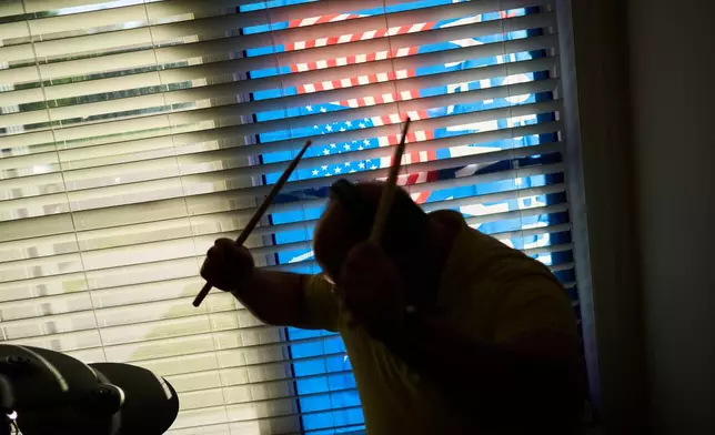 Brian Glick, who is fighting to recover the $575,000 stolen from him by a scammer online, plays the drums, Wednesday, June 25, 2025, at his home in Ballston Lake, N.Y. (AP Photo/David Goldman)