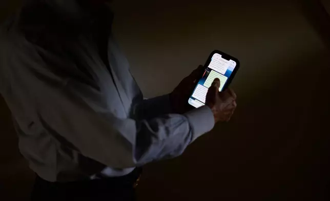 Simon, who was targeted by a scammer that stole $800,000 from his retirement savings and asked not to be identified by his full name because he's too ashamed to tell most of his family about the crime, scrolls through messages with the scammer on his phone, Wednesday, June 17, 2026, at his home in southeastern New York. (AP Photo/David Goldman)