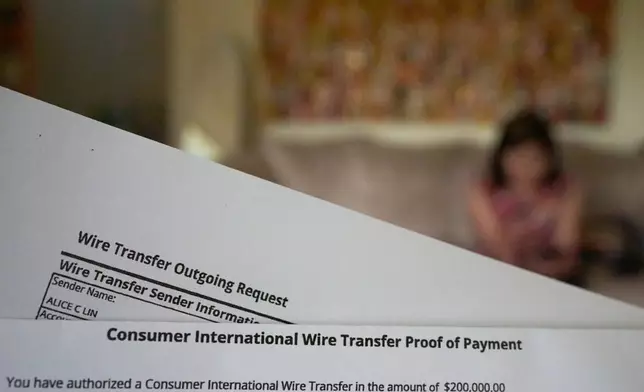 A copy of a wire transfer is seen as Alice Lin, who fought back to recover some of the $720,000 she and her late husband had saved over their lifetime which was stolen by an online scammer, sits on her couch at home, Sunday, May 10, 2026, in Alhambra, Calif. (AP Photo/David Goldman)