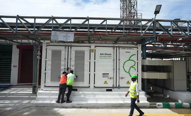 FILE - Team leader K. Sridhar, center, closes the doors after a routine check of lithium-ion batteries of 500-kilowatt battery energy storage system in Thiruvallur District, on the outskirts of Chennai, India, July16, 2024. (AP Photo/Mahesh Kumar A., File)