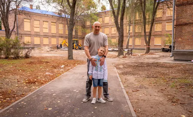 Yevhen Yurko, 41, and his son Darii, a 6-year-old first-grader, pose for a photo in the courtyard of a public school damaged by a Russian attack, in Kyiv, Tuesday, Sept. 1, 2026. (AP Photo/Dan Bashakov) CORRECTION: Name of child corrected from Dayri to Darii.