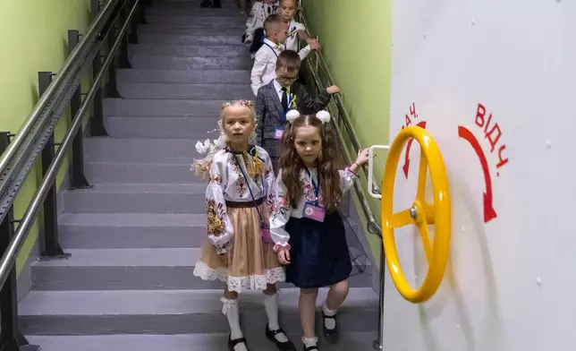 School children enter an underground school on their first day back, in Kharkiv, Ukraine, Tuesday, Sept. 1, 2026. (AP Photo/Andrii Marienko)