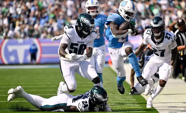 Tennessee Titans running back Tyjae Spears (2) runs from Philadelphia Eagles safety Andrew Mukuba (24), linebacker Jalyx Hunt (58) and cornerback Quinyon Mitchell (27) during the second half of an NFL football game, Sunday, Sept. 20, 2026, in Nashville, Tenn.(AP Photo/John Amis)