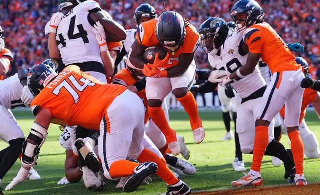 Denver Broncos running back Jonah Coleman, center, jumps into the end zone to score a touchdown against the Jacksonville Jaguars in the second half of an NFL football game in Denver, Sunday, Sept. 20, 2026. (AP Photo/David Zalubowski)