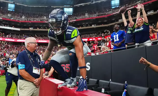 Seattle Seahawks wide receiver Jaxon Smith-Njigba jumps back onto the field after celebrating his touchdown against the Arizona Cardinals by giving the ball to fans during the second half of an NFL football game in Glendale, Ariz., Sunday, Sept. 20, 2026. (AP Photo/Ross D. Franklin)
