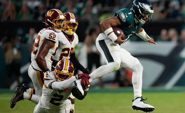 Philadelphia Eagles quarterback Jalen Hurts (1) is grabbed by Washington Commanders cornerback Amik Robertson (2) as he scramble during the second half of an NFL football game, Sunday, Sept. 13, 2026, in Philadelphia. (AP Photo/Matt Slocum)