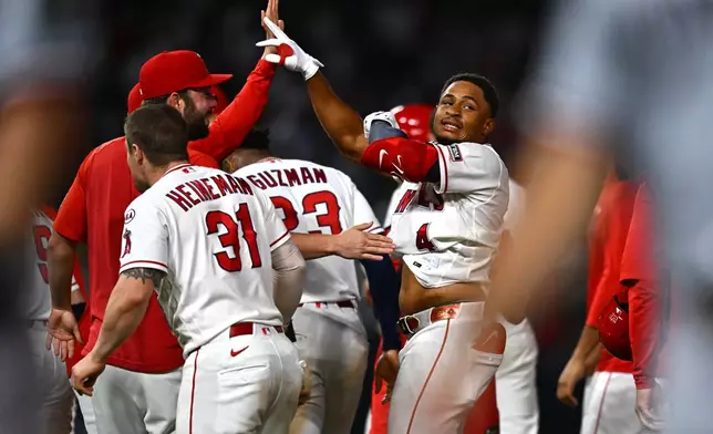 Los Angeles Angels' Christian Moore (4) is greeted by teammates after hitting a walk-off single during the 11th inning of a baseball game against the Minnesota Twins, Saturday, Sept. 19, 2026, in Anaheim, Calif. (AP Photo/William Liang)