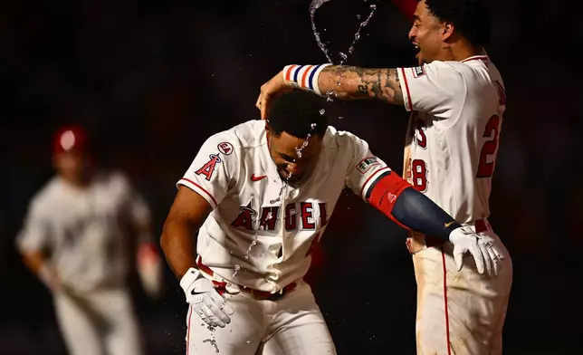 Los Angeles Angels' Christian Moore, center, is greeted by Jose Siri, right, after hitting a walk-off single during the 11th inning of a baseball game against the Minnesota Twins, Saturday, Sept. 19, 2026, in Anaheim, Calif. (AP Photo/William Liang)