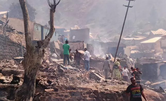 People walk through smoke after a fire at a school killed several people in Bukavu, Congo, Thursday, Sept. 10, 2026. (AP Photo/Janvier Barhahiga)