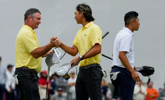 International teams' Ryan Fox, of New Zealand, left, greets teammate Min Woo Lee, of Australia, as USA teams' Collin Morikawa walks off the 18th green after their Presidents Cup golf tournament second round foursomes match at Medinah Country Club, Friday, Sept. 25, 2026, in Medinah, Ill. (AP Photo/Chris Carlson)