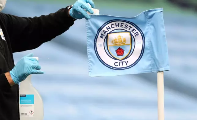 FILE - A groundsman disinfects a corner flag ahead of the English Premier League soccer match between Manchester City and Burnley at Etihad Stadium, in Manchester, England, Monday, June 22, 2020. (AP Photo/Martin Rickett,Pool, File)