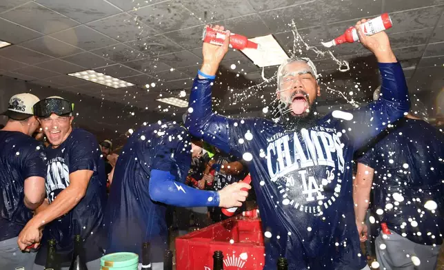 Los Angeles Dodgers left fielder Teoscar Hernández, right, celebrates with teammates in the clubhouse after the team clinched their fifth consecutive NL West division title after a baseball game against the Cincinnati Reds, Thursday, Sept. 17, 2026 in Cincinnati. (AP Photo/Tanner Pearson)