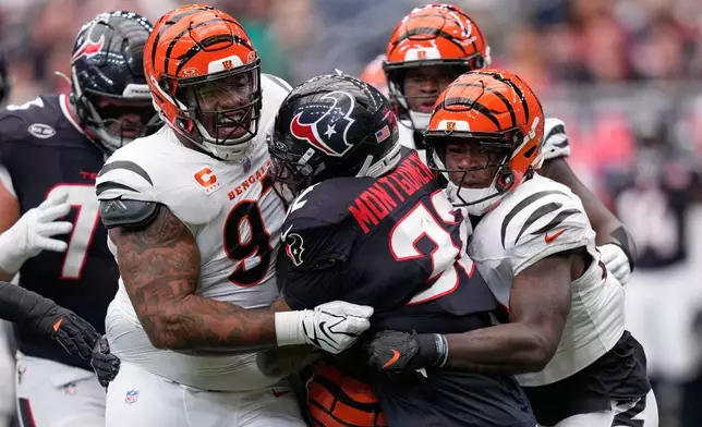 Cincinnati Bengals defensive tackle Dexter Lawrence II, left, and inside linebacker Oren Burks, right, tackle Houston Texans running back David Montgomery, center, for no gain during the first half of an NFL football game in Houston, Sunday, Sept. 20, 2026. (AP Photo/David J. Phillip)