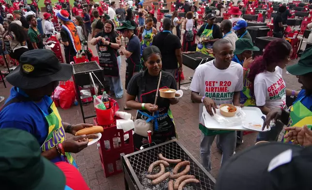 Participants help themselves to food during an attempt to break a world record for the most people cooking simultaneously at a barbecue at Loftus Versfeld Stadium, Pretoria, South Africa, Thursday, Sept. 24, 2026. (AP Photo/Alfonso Nqunjana)